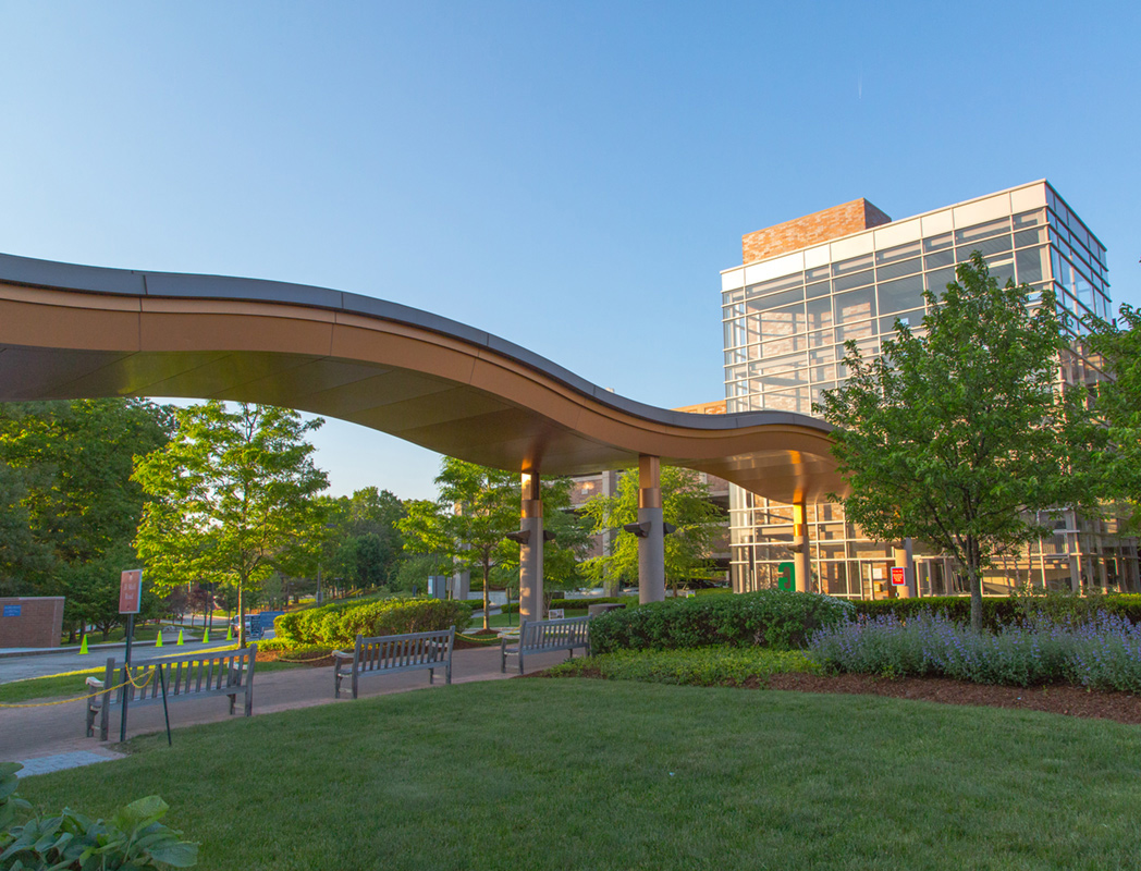Lahey's modern building with a curved roof and glass windows, surrounded by greenery.