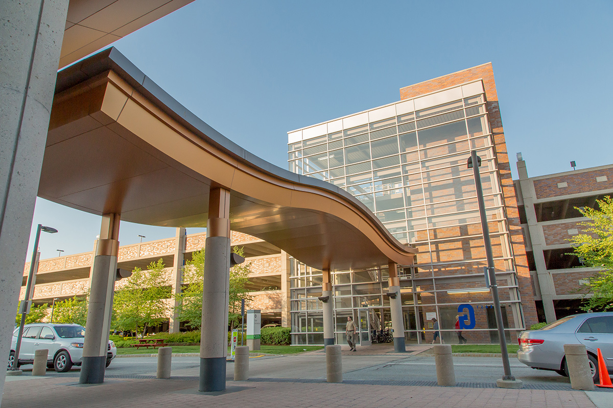 Exterior of Lahey Clinic showing a curved awning, glass walls, and a parking garage