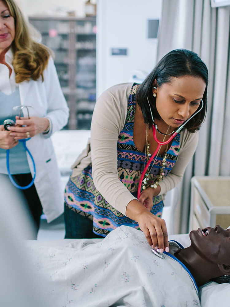 Medical resident using stethoscope on medical mannequin