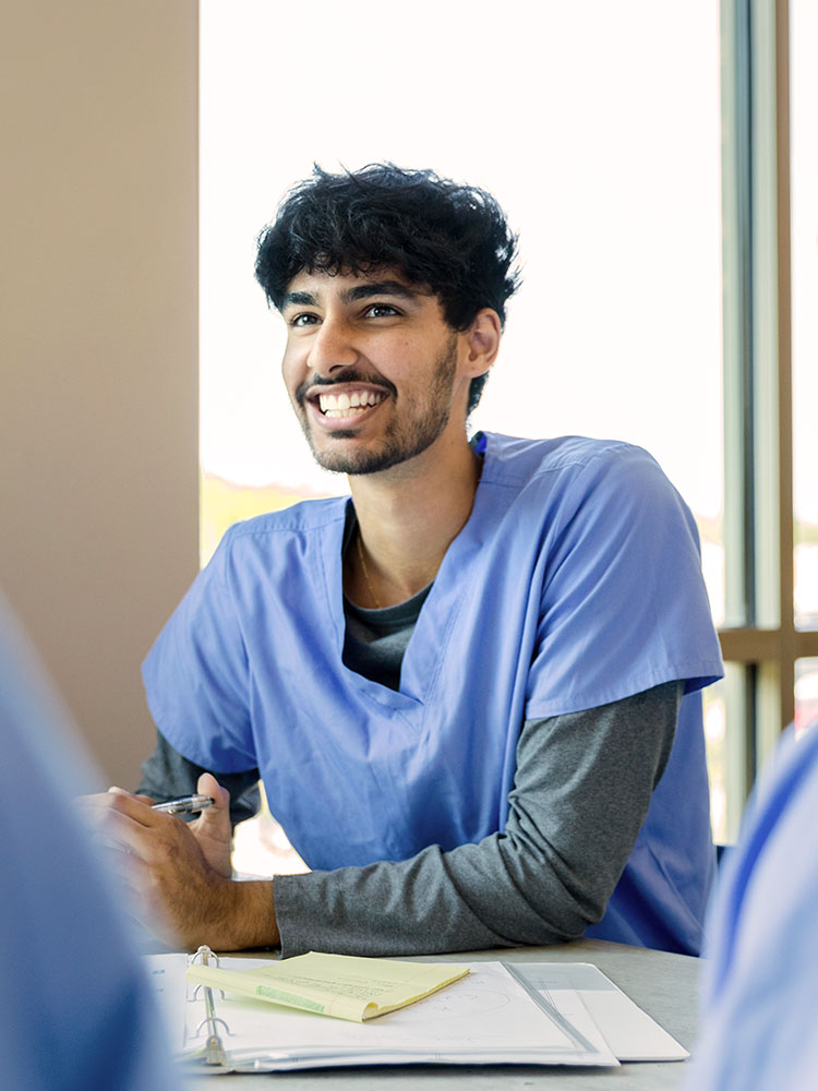 Smiling graduate medical student sitting at a desk