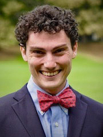 Man with curly hair and a red bow tie smiling
