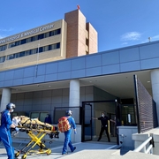 Two med flight workers in blue suits wheel a stretcher into Lahey hospital