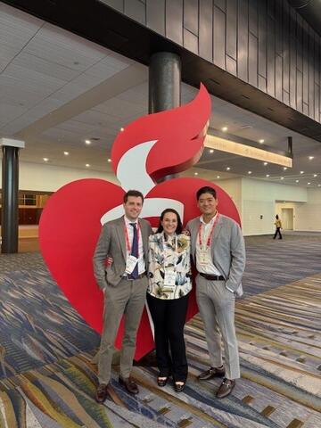 Dr. Krawisz, Dr. Kim and Dr. Andrew Oseran pose in front of the AHA logo