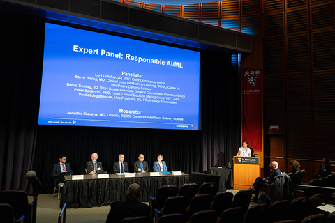 An expert panel sits at a table with a large screen behind them showing "Expert Panel: Responsible AIM"