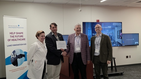 Four people standing in a room with a certificate being handed to the person in the white coat