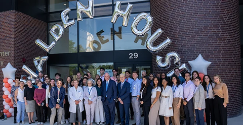 A group of people pose for a photo in front of a building named Alden House.