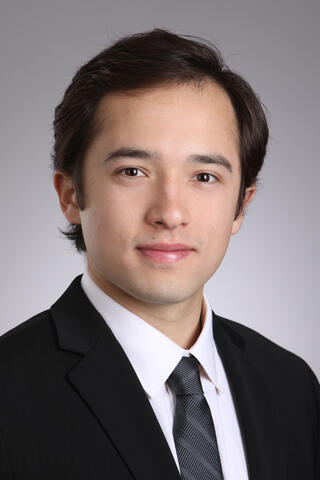 Headshot of a smiling young man in a business suit