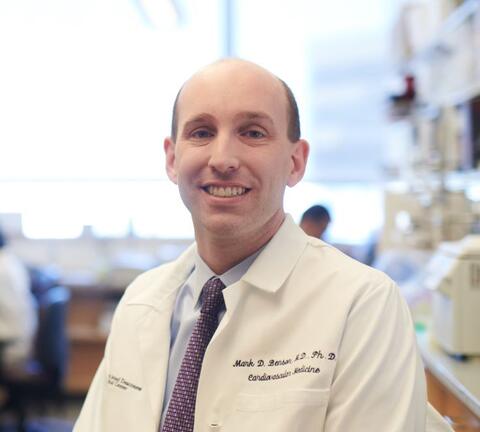 Man in a white lab coat smiling