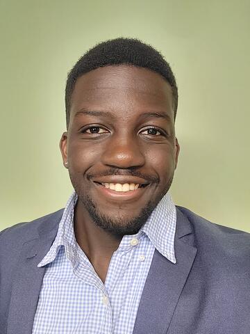 Man in a blue suit smiling in front of a green background
