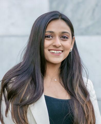 Radhe Shah smiling in front of a grey background