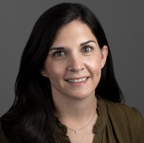 Smiling woman with long black hair wearing a brown blouse and a necklace.