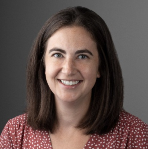 A woman in a red polka-dot shirt smiles for a portrait.