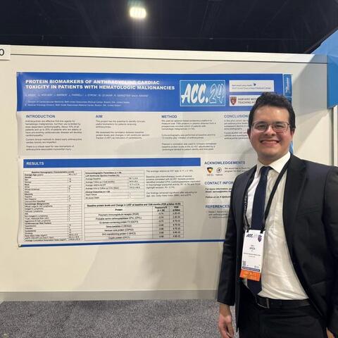 Man in a suit standing in front of a board with a poster on it.