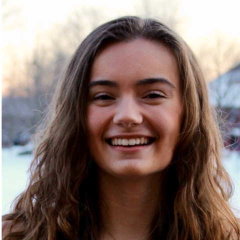 Woman with long brown hair smiling at camera.