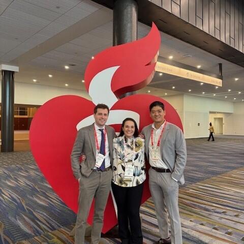 Dr. Krawisz, Dr. Kim and Dr. Andrew Oseran pose in front of the AHA logo