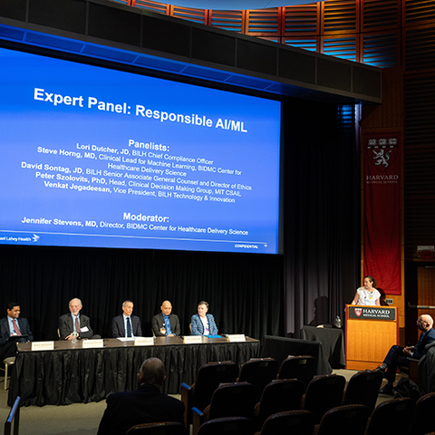 An expert panel sits at a table with a large screen behind them showing "Expert Panel: Responsible AIM"