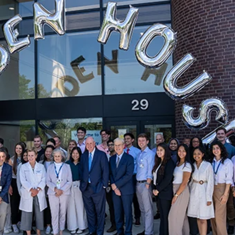 A group of people pose for a photo in front of a building named Alden House.