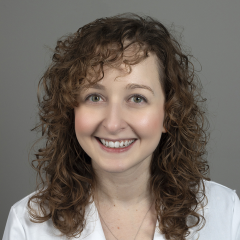 Brooke Lubinski, woman in a white coat, smiling at camera.
