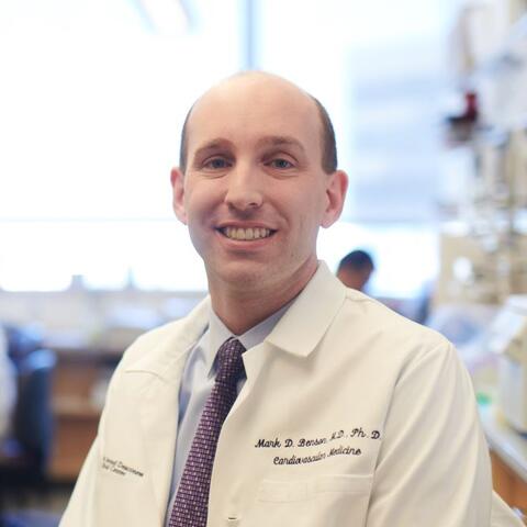 Man in a white lab coat smiling