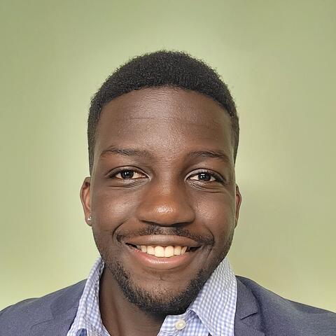 Man in a blue suit smiling in front of a green background