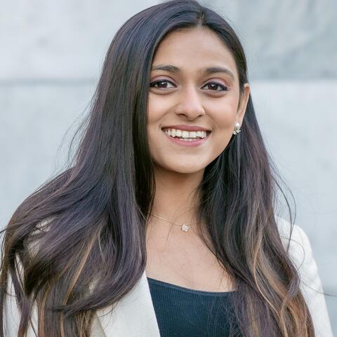 Radhe Shah smiling in front of a grey background