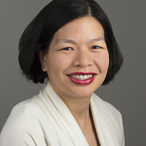 Woman with short black hair and red lipstick smiles at the camera