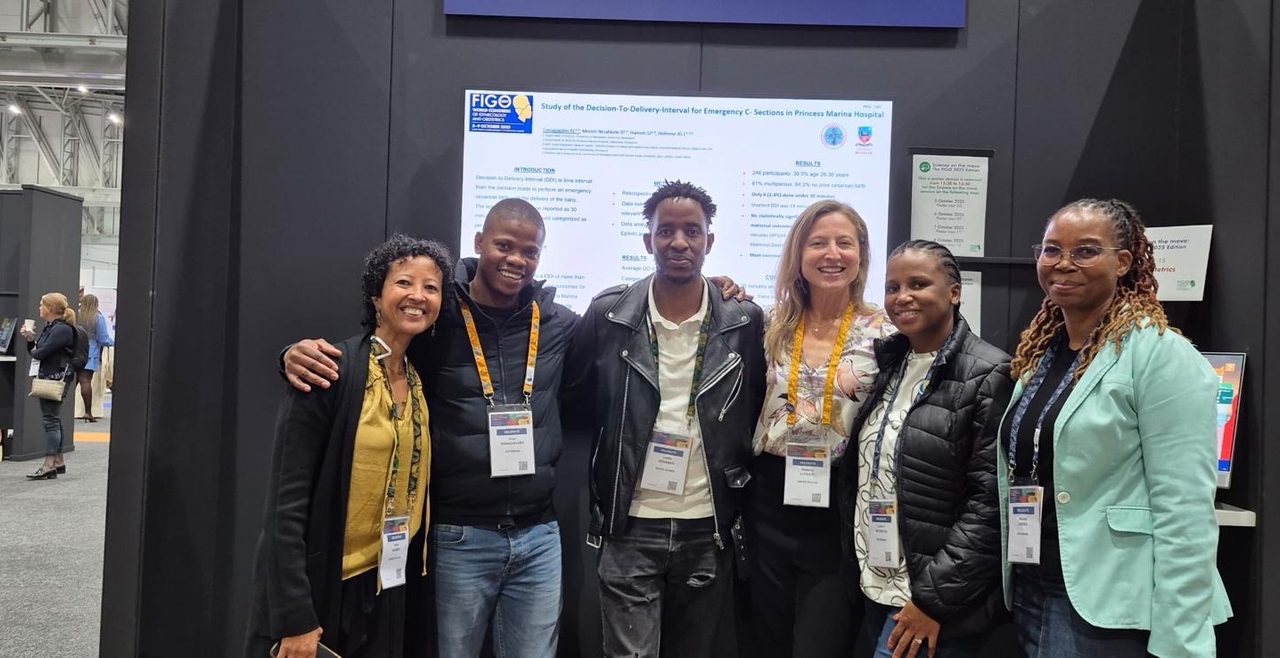 Rebecca Luckett, Leatile Sedabadi, and team pose in front of poster