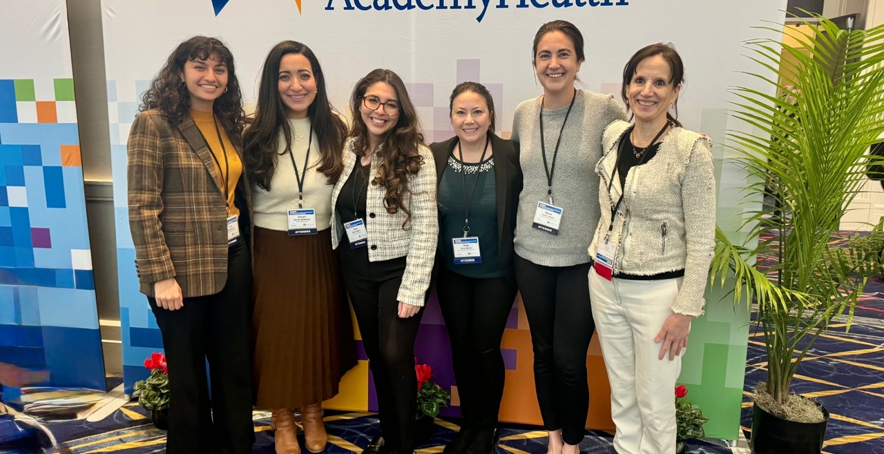 Six women stand behind a wall with the AcademyHealth logo.