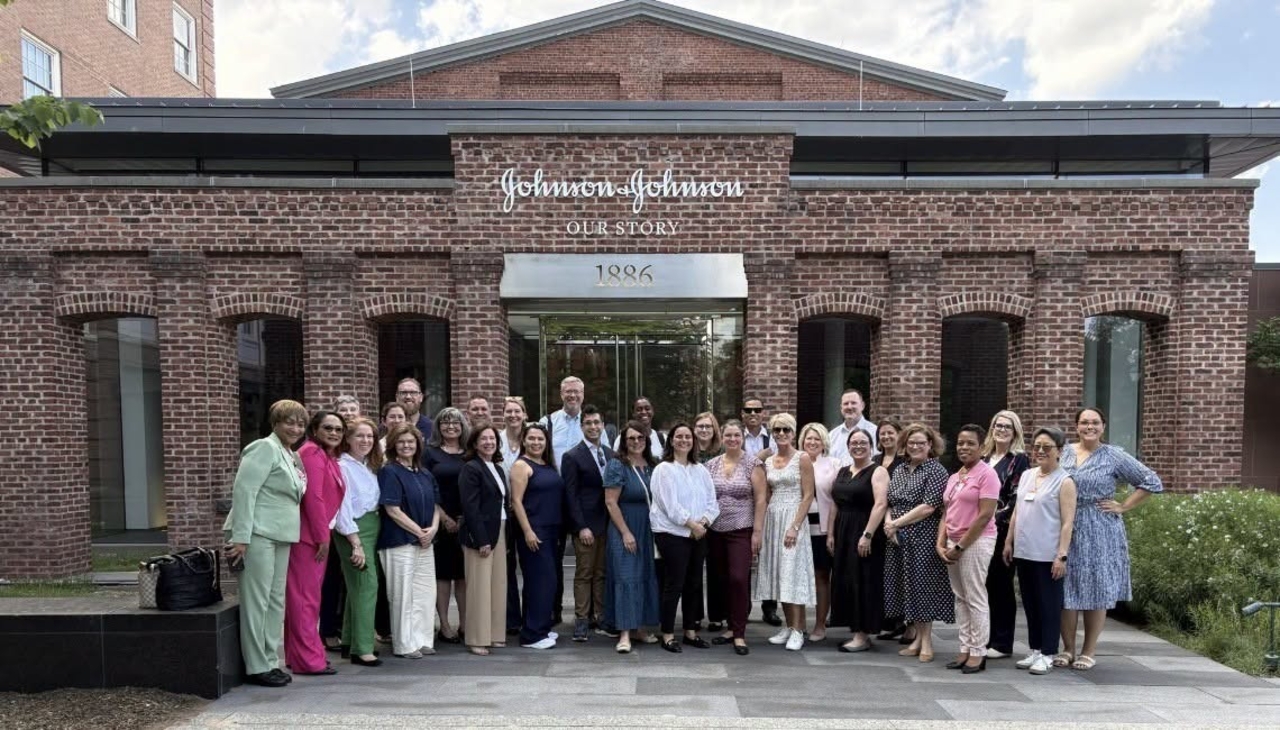 A group of people stands outside a brick building with a sign that says Johnson &amp; Johnson.