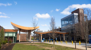 Entrance to Lahey with a wooden canopy and glass wall under a blue sky