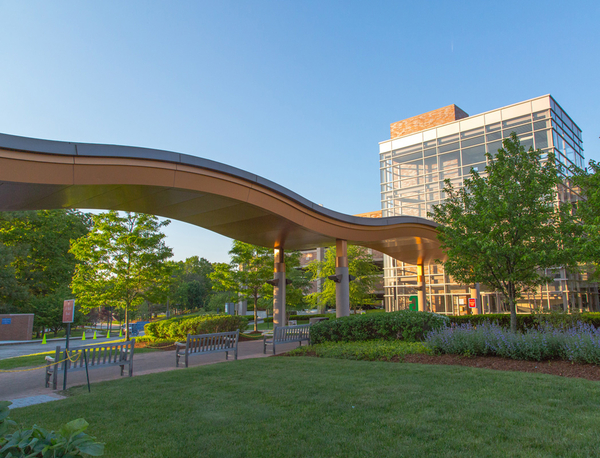 Lahey's modern building with a curved roof and glass windows, surrounded by greenery.