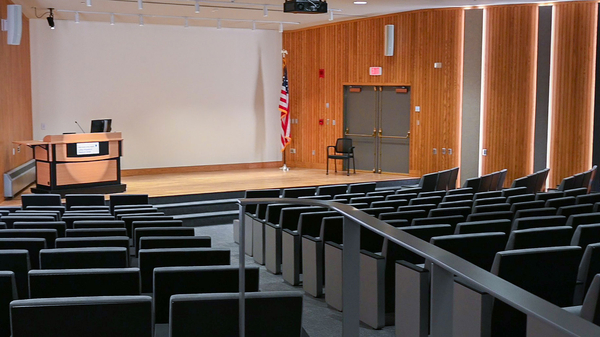 Empty auditorium with wooden walls and rows of chairs.