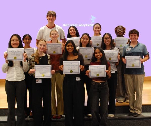 Several people in a group holding certificates, standing on a stage.