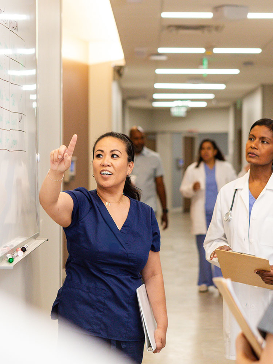 Female doctor pointing to white board for students